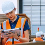 Workers in manufacturing plant looking at ipad.